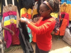 Emily Mugure checks out a secondhand jacket in Nairobi's Toi market. (M. Yusuf/VOA)