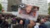 A protester holds up a poster with a photo of German Chancellor Angela Merkel declaring her "Guilty" at an anti-migrant rally in Chemnitz, eastern Germany, Sept. 1, 2018.