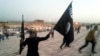 FILE - An Islamic State fighter holds an IS flag and weapon on a street in Mosul, Iraq, in June 2014.