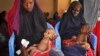 FILE - Malnourished babies are held by their mothers, both of whom fled the drought in southern Somalia, at a feeding center in a camp in Mogadishu, Somalia, Feb. 25, 2017.