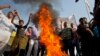 Pakistani Christians chant slogans after they burn a tire during a demonstration demanding that the government rebuild their homes after they were burned down following an alleged blasphemy incident, in Islamabad, Pakistan, March 10, 2013.