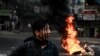 A protester with his face painted stands near a burning makeshift barricade during a protest against the military coup, in Yangon, March 30, 2021. 