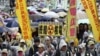 Demonstrators in raincoats and umbrellas march with banners and placards during an anti-nuclear protest on a street, amid rainfall in Taipei, March 8, 2014.
