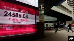 Peatones caminan frente a una pizarra electrónica de un banco que muestra los resultados de la bolsa de Hong Kong, el 14 de octubre de 2020.