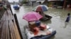Residents use makeshift floats as others cross a makeshift bridge built over a flooded road in suburban Pasig, east of Manila, Philippines, August 15, 2012.