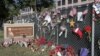FILE - Flowers and American flags honoring the 14 victims of the Dec. 2, 2015, terror attack in San Bernardino, California, Dec. 29, 2015. Apple refused to help the FBI unlock an iPhone belonging to one of the assailants.