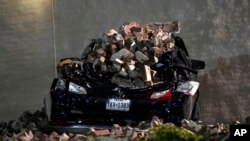 Un automóvil aplastado por ladrillos desprendidos del muro de un edificio yace en un estacionamiento del centro de Houston el jueves 16 de mayo de 2024, luego del paso de una tormenta. 