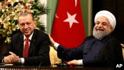 FILE - Iran's President Hassan Rouhani, right, laughs during a during a joint press conference with Turkey's President Recep Tayyip Erdogan following their meeting at the Saadabad Palace in Tehran, Iran, Oct. 4, 2017.