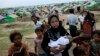 An internally displaced Rohingya woman holds her newborn baby surrounded by children in the foreground of makeshift tents at a camp for Rohingya people in Sittwe, northwestern Rakhine State, Burma, May13, 2013. 