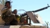 FILE - A fighter of the Syrian Democratic Forces gestures in the village of Baghuz, Deir el-Zour province, Syria, March 18, 2019.