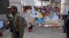 FILE - A soldier stands near a woman reading messages left by people for the victims of the Taliban attack on a school, in Peshawar, Pakistan, Dec. 23, 2014. 