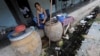 A Burmese migrant washes dishes outside her room at an apartment building housing Burmese migrant workers in Mahachai, an industrial area south of Bangkok, August 25, 2010.
