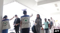 En un control de inmigración en Myawaddy, Birmania, cerca de la frontera tailandesa, funcionarios toman la temperatura a quienes arriban al lugar, como medida para reducir el riego de contagio.