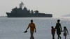 FILE - A Filipino family stroll the beach at Subic Bay as the USS Harpers Ferry approaches to dock, Feb. 17, 2006. 