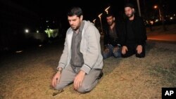 Tres de los cuatro ex prisioneros oran frente a la embajada de EE.UU en Uruguay durante su protesta pacífica.