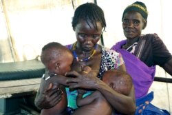 FILE - A mother breastfeeds her severely malnourished eight-month-old twins in a health clinic in Pibor, South Sudan, Dec. 16, 2020.