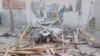 FILE - People stand near the damage following an attack on a mosque in the town of Gamboru in Borno state, Nigeria, Jan. 3, 2018.