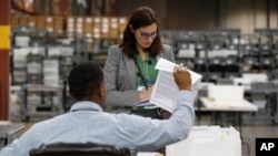 Supervisores clasifican las boletas de votación durante un recuento el miércoles 14 de noviembre de 2018, en West Palm Beach, Florida.