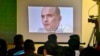 FILE - Journalists look a image of Indian naval officer Kulbhushan Jadhav, who was arrested in March 2016, during a press conference by Pakistan's army spokesman and the Information Minister, in Islamabad, Pakistan, March 29, 2016.