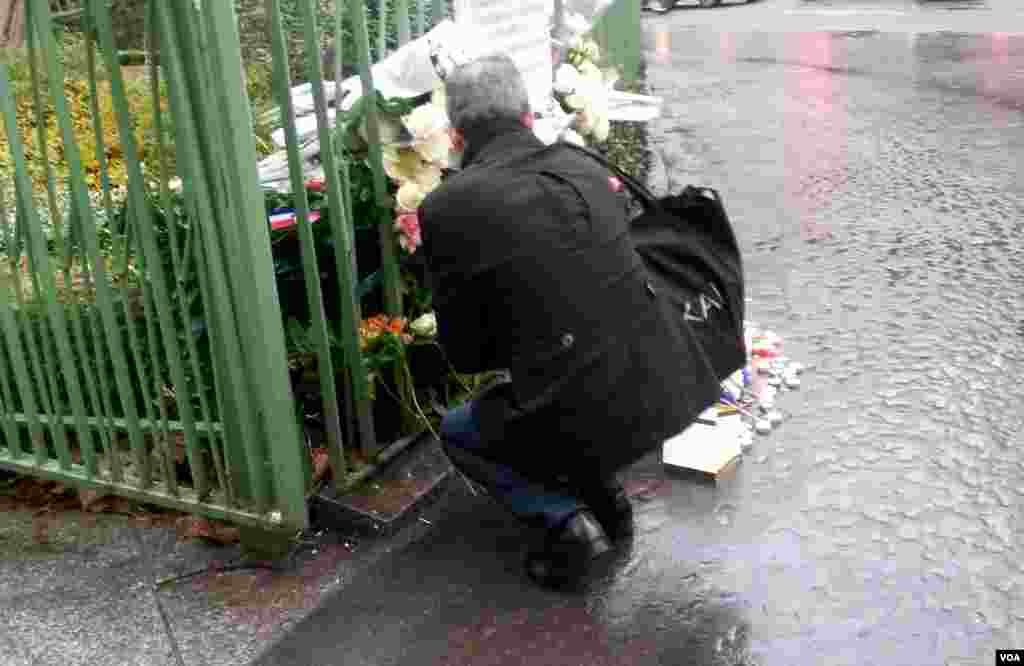 A man kneels by a plaque near Cafe Bonne Biere where jihadists killed 5 people last year, in Paris, Nov. 13, 2016. (L. Bryant/VOA)