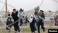 Sirios corren para huir de la ciudad siria de Ras al-Ain a la ciudad fronteriza turca de Ceylanpinar. 