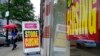 FILE - A passerby walks past a business storefront with store closing signs in Boston. U.S. unemployment benefit claims jumped sharply in the first week of December 2020.