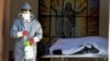A health worker disinfects the area next to a coffin with the remains of a recently deceased resident of the San Jose nursing home in Cochabamba, Bolivia, July 16, 2020.