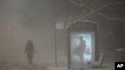 Una mujer camina hacia una parada de autobús en Dr. Martin Luther King Drive en Chicago mientras un hombre espera en la parada durante las horas previas al amanecer del miércoles 2 de febrero de 2022.