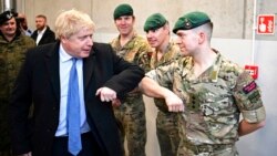 El primer ministro del Reino Unido, Boris Johnson, saluda a un miembro de la Marina británica durante una visita a la base militar de Brigada Pancema, en Varsovia, el 10 de febrero de 2022.