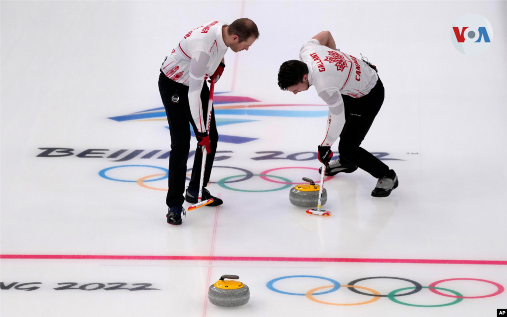 Los canadienses Brett Gallant, a la derecha, y Geoff Walker barren el hielo durante una competencia de semifinales de curling masculino entre Canadá y Suecia.