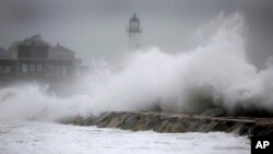 Las olas chocan contra el faro Scituate, el viernes, en Scituate, Massachusetts.