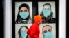 n this Nov. 16, 2020, file photo, a runner passes by a window displaying portraits of people wearing face coverings to help prevent the spread of the coronavirus in Lewiston, Maine. A deadly rise in COVID-19 infections is forcing state and local officials to adjust their blueprin
