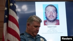 Seorang petugas polisi berdiri di samping layar yang menampilkan gambar tersangka penembak di Balai Kota di Lewiston, Maine, AS 27 Oktober 2023. (Foto: REUTERS/Kevin Lamarque)