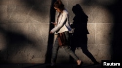 FILE - A young woman looks at her mobile phone early morning in Westminster, London, Britain, Oct. 10, 2016. The suicide rate among British teenagers has nearly doubled, and critics say social media giants are abetting them.
