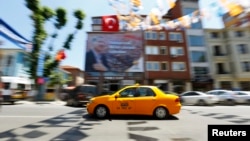 FILE - A yellow taxi drives past a poster depicting Turkey's Prime Minister Tayyip Erdogan in Istanbul.
