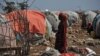 FILE - A Somali woman carries wood to make a shelter in an internally displaced people (IDP) camp, Dec. 18, 2018.