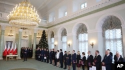 FILE - Polish Prime Minister Mateusz Morawiecki, left, along with the new ministers of his Cabinet speaks during the swearing-in ceremony at the Presidential Palace in Warsaw, Poland, Jan. 9, 2018. 
