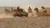 FILE - Fighters ride in pickup trucks as forces loyal to Yemen's Saudi-backed government clash with Houthi rebels in al-Jadaan, in Yemen's Marib governorate, Nov. 22, 2020.
