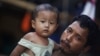 A migrant worker from Burma holds his daughter in front of their house in the port town of Mahachai, near Bangkok, September 24, 2011. 
