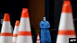 FILE - Health care workers wait for patients to be tested at a walk-in COVID-19 testing site in Arlington, Virginia, May 12, 2020.