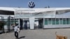 FILE - An employee leaves the Volkswagen plant as the company temporarily closes its factories in Mexico amid growing worries over the spread of the coronavirus disease, in Puebla, Mexico, March 29, 2020.