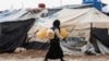 FILE - A woman carries jerry cans to fill them up with water at the Kurdish-run al-Hol camp for the displaced where families of Islamic State (IS) foreign fighters are held, in the al-Hasakeh governorate in northeastern Syria on Dec. 9, 2019.