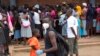 FILE: A man wearing a mask is seen near a food queue in Harare, Zimbabwe, March 25, 2020. 