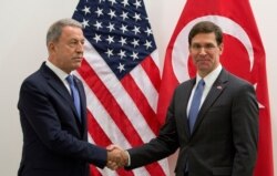 Acting U.S. Defense Secretary Mark Esper, right, greets Turkish Defense Minister Hulusi Akar prior to a meeting of NATO defense ministers at NATO headquarters in Brussels, Belgium, June 26, 2019.