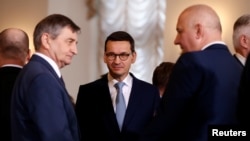 Poland's Prime Minister Mateusz Morawiecki speaks with Marek Kuchcinski, left, speaker of parliament, and Joachim Brudzinski, newly sworn-in Interior Minister, after a ceremony at Presidential Palace in Warsaw, Jan. 9, 2018. 