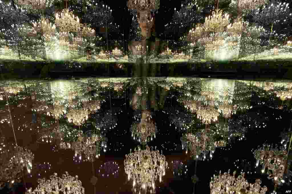Seorang petugas galeri seni berpose dengan karya seni &quot;Chandelier of Grief&quot;, karya artis Jepang Yayoi Kusama, yang dipamerkan di London.