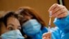 Nurses, Ines, left, and Valerie prepare a Pfizer-BioNTech COVID-19 vaccine to be administered to a health care worker at a coronavirus vaccine center in Poissy, France, Friday, Jan.8, 2021. 