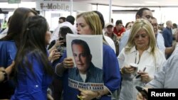 Una mujer sostiene una foto de Manuel Rosales junto a la esposa de Rosales, Eveling Trejo de Rosales, mientras aguardaban su llegada al aeropuerto de Maracaibo, Venezuela, el jueves 15 de octubre de 2015.