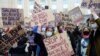 FILE - Women hold placards during a demonstration to call for gender equality and demand an end to violence against women, on International Women's Day in Brussels, Belgium, March 8, 2021. 