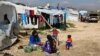 FILE - Syrian women prepare food for their family outside their tents, at a Syrian refugee camp in the town of Bar Elias, in Lebanon's Bekaa Valley, March 29, 2016. 